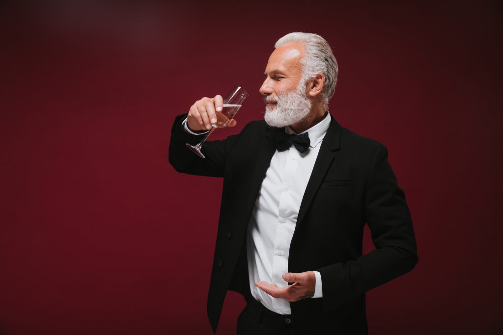 bearded-man-suit-drinks-champagne-smiling-grey-haired-adult-guy-white-shirt-posing-with-wine-glass-burgundy-background.jpg
